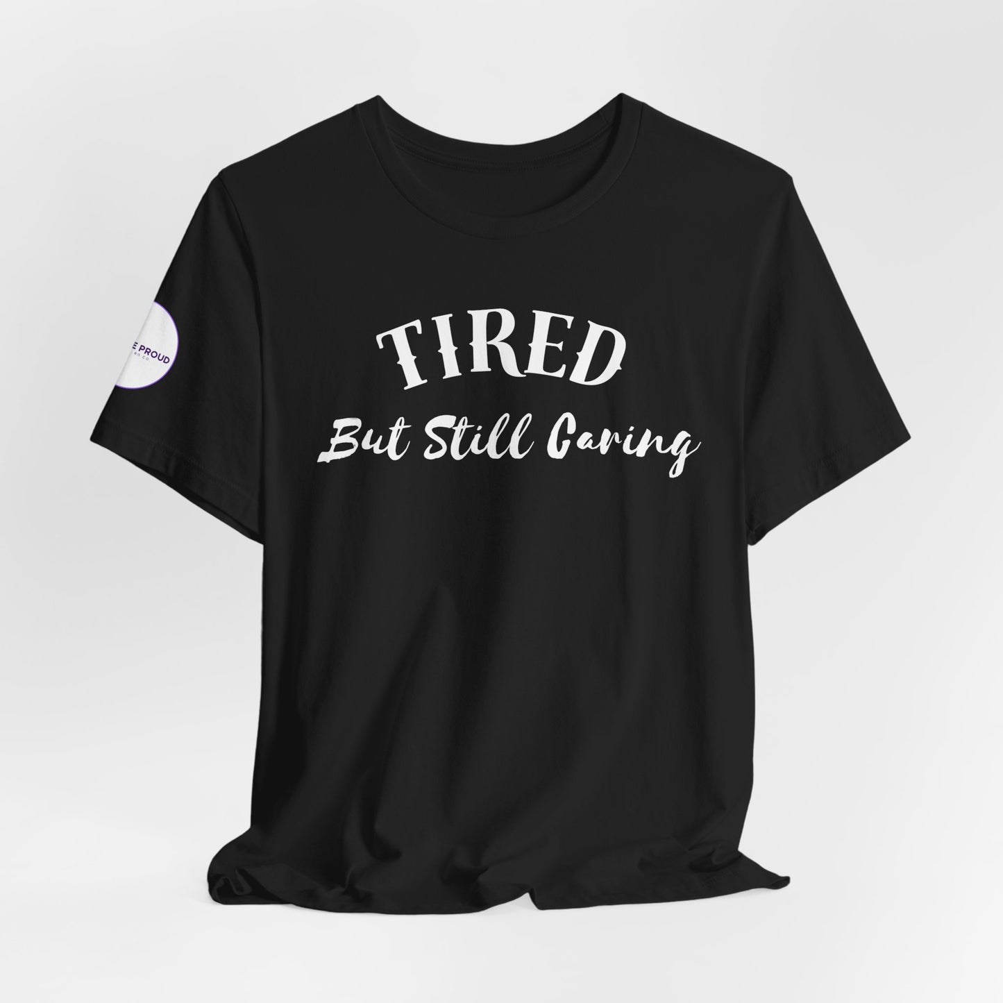 Side view of Tired But Still Caring T-Shirt with crew neck fit